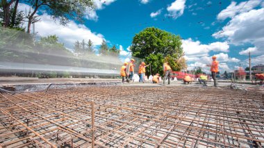 Tramvay rayları onarılan ve bakım süreleri yüksek olan yol inşaatı. Metal bir şebekeye beton dökülüyor. Birçok işçiyle kavşağın ortası.
