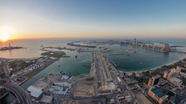 Palm Jumeirah Adası gün gece geçiş timelapse için hava gün batımı manzarası. Üstten görünüm ışıklı Villaları, otelleri ve yatlar ile akşam. Yeni cruise terminal inşaat süreci