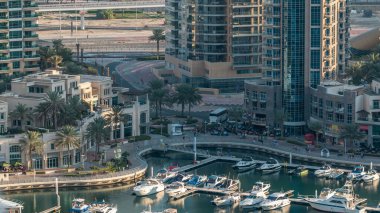 Lüks Dubai Marina Kanalı 'ndan geçen tekneler, yatlar ve palmiyeli gezinti güvertesi, akşamdan önce yukarıdan bir manzara. Dubai, Birleşik Arap Emirlikleri