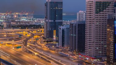 Dubai Yat Limanı gökdelenler hava üstten görünüm güneş doğmadan önce Jlt gelen Dubai gece gün timelapse, Birleşik Arap Emirlikleri için. Işıklı modern kuleleri ve kavşak ile Şeyh zayed yolu üzerinde trafik