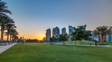 Gün batımında Doha 'nın yüksek katlı zaman diliminde, Hotel Park' tan yeşil çimenli ve ön planda suni tepe ile görüldü. Gökdelenler ve palmiyeler