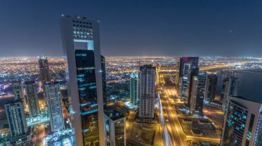 Katar 'ın Doha Zaman Çizelgesi' nde Batı Körfezi bölgesinin ufuk çizgisi. Aydınlatılmış modern gökdelenler geceleri çatıdan gökyüzü manzarası