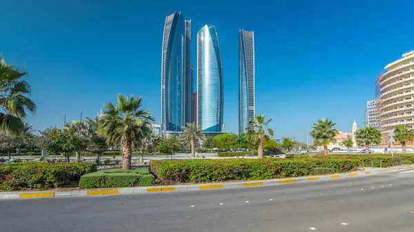 Ebu Dabi 'nin gökdelenleri Etihad Kuleleri' nin binaları zaman atlamalı. Avuç içleriyle ve trafiğiyle park et. Güneş cam yüzeyden yansıyor. Birleşik Arap Emirlikleri