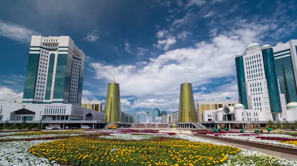 Nur-Sultan şehrinde Kazakistan Cumhuriyeti Senatosu 'nun inşa edilmesi. Ön planda çiçek açmış. Arka planda Nurzhol Bulvarı. Yazın mavi bulutlu gökyüzü