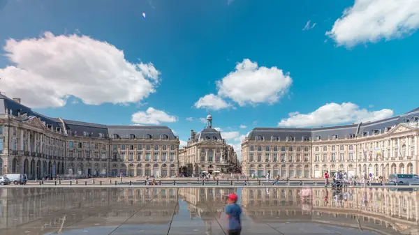Place de la Bourse ve Miroir d 'eau hiperlapse Bordeaux, Fransa' da, tarihi mimariyi yansıtıyor. Turistler şehir simgesi ve çeşmenin tadını çıkarıyorlar. Trafik ve tramvay zamanı geçiyor..