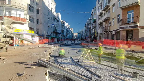 Beton, yol onarım inşaatı için bir moloz yığınında çalışıyor. Bir sürü işçi ve mikser makinası var. Tramvay raylarının yeniden inşası