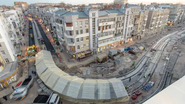 Asfalt kaldırım taşı, paten ve kamyon asfaltlama sırasında yol onarım alanında. Çadırın altındaki tramvay raylarının havadan görünüşü. Yol yapım ekipmanları. Yol onarımı yapan inşaat işçileri.