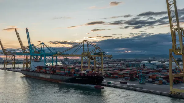 Barcelona 'nın deniz kargo limanı ve konteynır terminalinin günbatımı görüntüsü Montjuic Hill zaman atlaması, Barcelona, Katalonya, İspanya. Gemiler vinçlerle yükleniyor. Seyahat terminalinden görüntüle