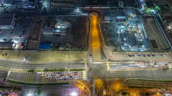 Bir büyük şehir gece timelapse bir yol kavşak hava üstten görünüm. Arabalar ve tramvay hattı ile UAE Dubai Yat Limanı bölgesinin kentsel peyzaj.