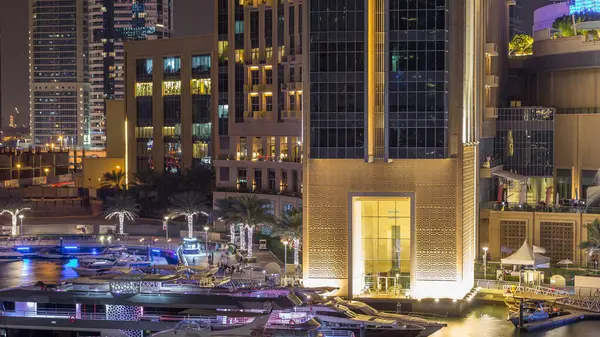 Dubai Marina 'nın hava görüntüsü, alışveriş merkezi, restoranlar, kuleler ve yatlar, Birleşik Arap Emirlikleri. Aydınlatılmış binalar ve liman manzaralı bir kanal.