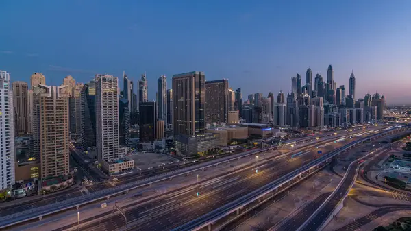Dubai Yat Limanı gökdelenler hava üstten görünüm güneş doğmadan önce Jlt gelen Dubai gece gün timelapse, Birleşik Arap Emirlikleri için. Işıklı modern kuleleri ve Şeyh zayed yolu üzerinde trafik.