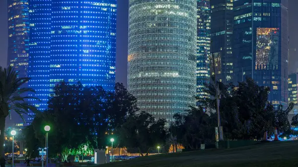 Doha 'nın yüksek katlı bölgesinde gece vardiyası, parktan görülmüş. Batı körfezinde aydınlatılmış gökdelenler ve palmiyeler