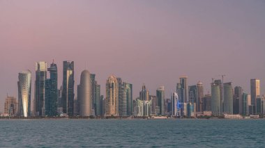 Arap şehri Doha 'nın ufuk çizgisi gece gündüz Katar' daki geçiş zamanı, gün doğumundan hemen önce aydınlık gökdelenlerle yakalandı. Corniche Gezinti Alanından Görünüm