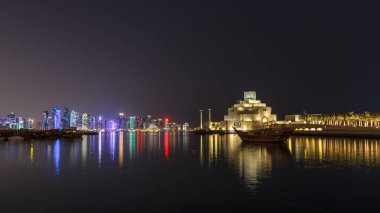 Katar 'ın Doha kentindeki eski dhow liman gecesi hiperhızının panoramik bir görüntüsü. Arka planda West Bay silueti var. Arka planda modern gökdelenler ve müzeler ve ön planda eski tekneler