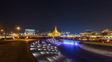 Souq Waqif Parkı 'ndaki küçük amfi tiyatro Doha' da gece vakti hızlandırılmış hiperhızlandırma, bitki örtüsü ve uzak mesafedeki binalar, aydınlatılmış İslam merkezi de dahil olmak üzere.