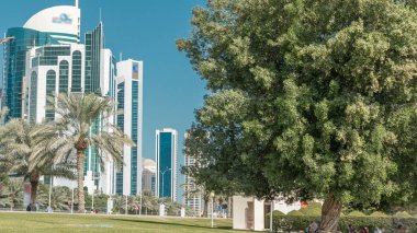 Batı Körfezi 'ndeki Doha' s Corniche 'de modern gökdelenler ve ağaçlarla, Katar. Corniche, fantastik gezinti yerleri, su sporları, geleneksel dhow yarışları ve daha pek çok şeyle bilinen popüler bir egzersiz mekanıdır.