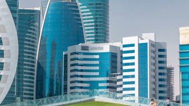 Doha 'nın yüksek katlı zaman dilimi. Otel Parkı' ndan yeşil çimenli ve ön planda suni tepe ile görülüyor. Gökdelenler ve palmiyeler
