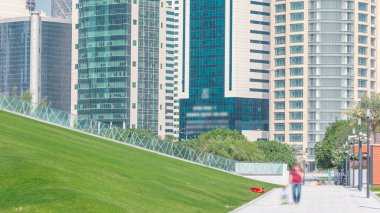 Doha 'nın yüksek katlı zaman dilimi. Otel Parkı' ndan yeşil çimenli ve ön planda suni tepe ile görülüyor. Gökdelenler ve palmiyeler
