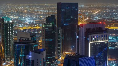 Katar 'ın Doha Zaman Çizelgesi' nde Batı Körfezi bölgesinin ufuk çizgisi. Aydınlatılmış modern gökdelenler geceleri çatıdan gökyüzü manzarası. Yolda trafik vardı.