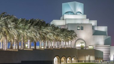 İslam Sanatları Müzesi, Katar 'ın Doha kentindeki çeşme zaman ayarlarıyla geceleyin aydınlandı. Avuçlar yana. MIA parkından görüntü. İslam eserlerinin en eksiksiz koleksiyonlarından biri.