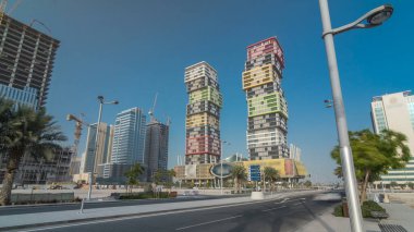 Katar 'ın başkenti Lusail' de bulunan renkli Al Marina İkiz Kuleleri binasıyla Doha Skyline zaman çizgisi aşırı hızlanması. Palmiyeler ve ağaçlar. Yolda trafik vardı.