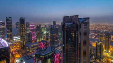 Batı Körfezi bölgesinin ufuk çizgisi Doha 'da günden geceye geçiş zamanı, Katar. Günbatımından sonra modern gökdelenlerin çatıdan görünüşü aydınlandı. Yolda trafik vardı.