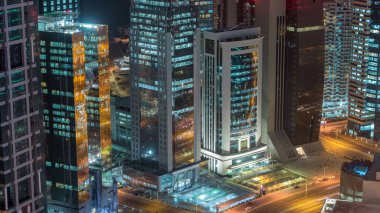 Katar 'ın Doha Zaman Çizelgesi' nde Batı Körfezi bölgesinin ufuk çizgisi. Aydınlatılmış modern gökdelenler geceleri çatıdan gökyüzü manzarası. Yolda trafik vardı.