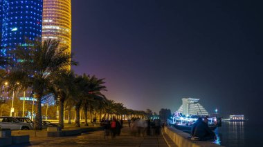 Geceleri Doha 'nın ufuk çizgisi Corniche zaman çizelgesi, Katar' dan görülebiliyor. Avuçlar önde. Aydınlatılmış gökdelenler ve kuleler