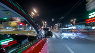 Hızlı arabanın yanından gelen bir drivelapse, gece caddesinde hızla ilerliyor. Işıklar yüksek hızda arabayı yansıtıyor. Modern bir şehrin hızlı ritmi. Bulanık hareket