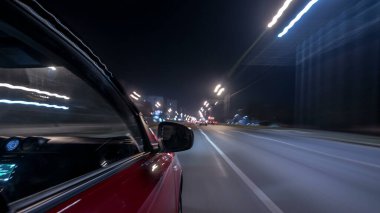 Hızlı sürüş yapan bir şehrin gece caddesinde, yüksek hızda ışık yansıtan bir yolda, hızlı sürüş yapan bir arabadan saçma sapan bir şehir görüntüsü. Modern bir şehrin hızlı ritmi. Bulanık hareket