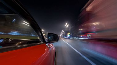 Hızlı sürüş yapan bir şehrin gece caddesinde, yüksek hızda ışık yansıtan bir yolda, hızlı sürüş yapan bir arabadan saçma sapan bir şehir görüntüsü. Modern bir şehrin hızlı ritmi. Bulanık hareket