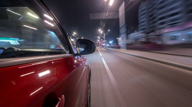 Hızlı sürüş yapan bir şehrin gece caddesinde, yüksek hızda ışık yansıtan bir yolda, hızlı sürüş yapan bir arabadan saçma sapan bir şehir görüntüsü. Modern bir şehrin hızlı ritmi. Bulanık hareket