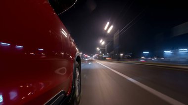 Hızlı sürüş yapan bir şehrin gece caddesinde, yüksek hızda ışık yansıtan bir yolda, hızlı sürüş yapan bir arabadan saçma sapan bir şehir görüntüsü. Modern bir şehrin hızlı ritmi. Bulanık hareket