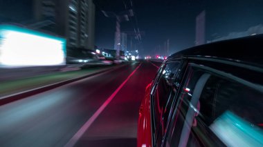 Hızlı sürüş yapan bir şehrin gece caddesinde, yüksek hızda ışık yansıtan bir yolda, hızlı sürüş yapan bir arabadan saçma sapan bir şehir görüntüsü. Modern bir şehrin hızlı ritmi. Bulanık hareket