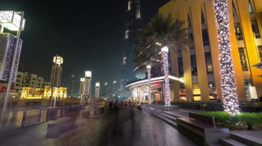 Dubai, BAE 'de çeşmenin yanında yürüyüş alanı var. İnsan yapımı gölde aydınlatılmış palmiyeler ve sokak lambaları