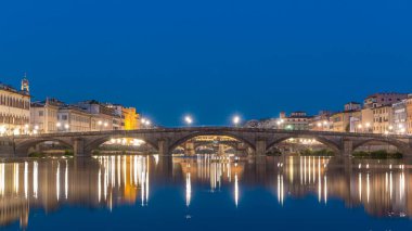 Alacakaranlık sahnesi Ponte Alla Carraia ve Santa Trinita 'nın (Kutsal Üçlü Köprü) gün batımından sonra suya yansıyan Arno Nehri üzerinde panoramik zaman geçişi sahnesi. Floransa, İtalya