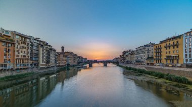 Arno Nehri üzerindeki şehir manzarası. Floransa 'da günbatımında Kutsal Üçlemeci Köprüsü' nün ünlü zamanlaması. Sudaki yansımalar. Yan taraftaki eski renkli evler