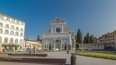 Santa Maria Novella Bazilikası 'nın Floransa' da eşkenar dörtgen zaman dilimi hiperhızlandırılmış görüntüsü. Çiçek yatakları ve yeşil çimenler. İnsanlar bankta oturuyor. Yazın mavi gökyüzü