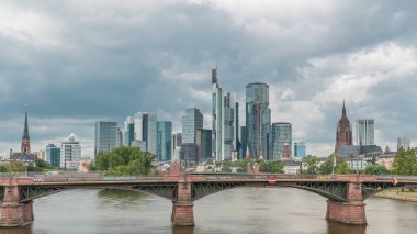 Frankfurt 'un, ana nehir ve Ignatz Bubis Köprüsü' yle olan hiperhızlandırılmış silueti. Gökdelenler ve kilise kuleleri dramatik bulutların altındaki suya yansıyor. Frankfurt, Almanya