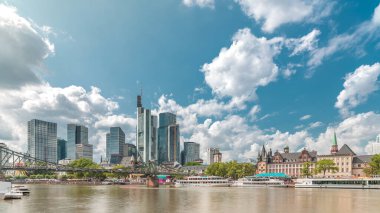 Almanya 'nın Frankfurt kentindeki ana nehrin üzerindeki tarihi Eiserner Steg' in (Demir Köprü) hiperlapesi. Gökdelenler ufuk çizgisi ve tarihi binalar bulutlarla dolu bir zaman dilimi altında suya yansıyor.
