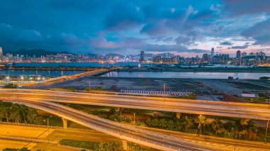 Hong Kong 'dan geceye geçiş, şehir merkezindeki Kowloon Körfezi' nin hava manzarası çatıdan yola çıkan trafik, arka planda güzel bulutlu gökyüzü olan şehir silüeti.