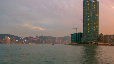 Star Ferry 'den Victoria Limanı' na diğer gemiler de günbatımında arka plan olarak Hong Kong 'un ufuk çizgisi ile birlikte seyir halinde.