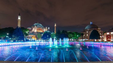 Hagia Sophia and Hamam in Istanbul old town night timelapse with blue illuminated fountain, Sultanahmet district, Turkey. Reflection on the water