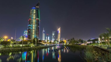 Parktaki müzik fıskiyeleri Kuveyt şehir manzaralı gece hipervaneli. Modern kuleler suya yansıyor. Körfezin kıyısında yer alıyor..