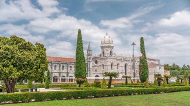 Mosteiro dos Jeronimos ve bahçede çimenliği olan yeşil ağaçlar, Lizbon, Portekiz 'in Belem bölgesinin zaman diliminde yer almaktadır. Manueline tarzı (Portekizce geç Gotik). Mavi gökyüzünde bulutlar