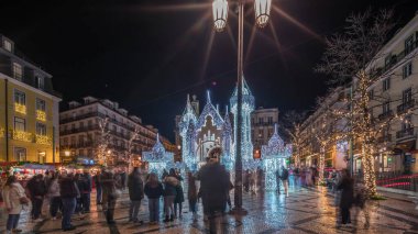 Lizbon, Portekiz 'deki Luis de Camoes meydanında aydınlatılmış şatoyla Noel süslemelerinin gece süreleri. İnsanlar şenlikli ışıkların ve tarihi mimarinin etrafında dolanıyor. Ön görünüm