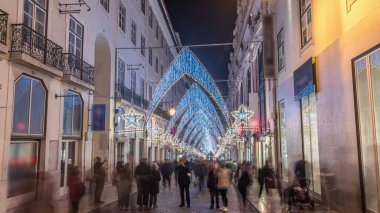 Lizbon şehir merkezindeki Chiado Carmo sokağındaki Noel ışıkları ve dekorasyonları gece aşırı hızlandı. İnsanlar aydınlanmış kemerlerin altında yürürler. Portekiz 'de festival dekorlu tatil atmosferi