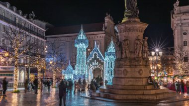 Lizbon, Portekiz 'deki Luis de Camoes meydanında aydınlatılmış şatoyla Noel süslemelerinin gece süreleri. İnsanlar festival ışıkları ve tarihi mimari etrafında yürüyorlar..