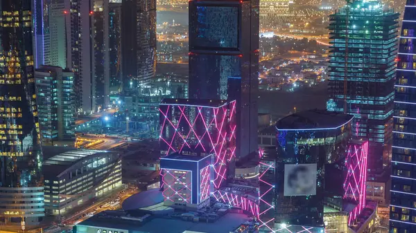 Katar 'ın Doha Zaman Çizelgesi' nde Batı Körfezi bölgesinin ufuk çizgisi. Aydınlatılmış modern gökdelenler geceleri çatıdan gökyüzü manzarası. Yolda trafik vardı.