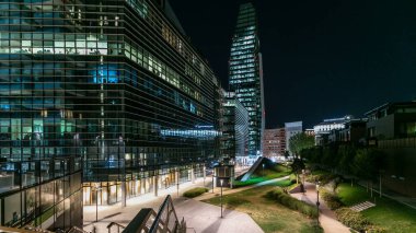 Milan Porta Nuova iş bölgesi, gece geçiş timelapse. Park ve windows gökdelenlerin ışıklar yeşil çim